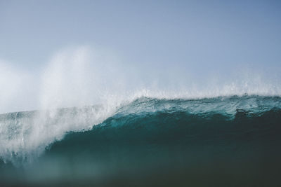 Sea waves splashing against clear sky