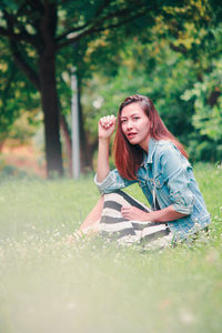 Beautiful young woman sitting on field