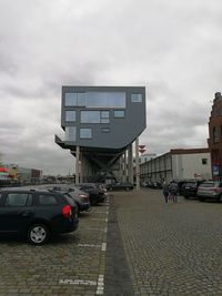 Cars on street by buildings against sky in city