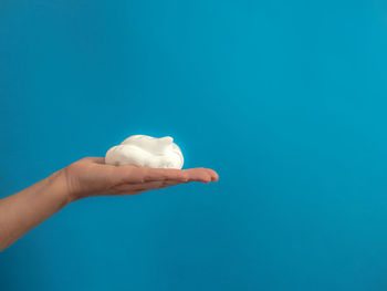 Close-up of hand holding blue background