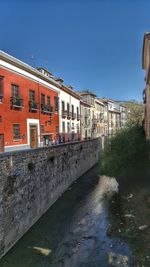 Canal by building against clear blue sky