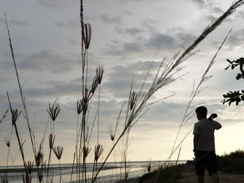 Rear view of silhouette man standing against sky during sunset