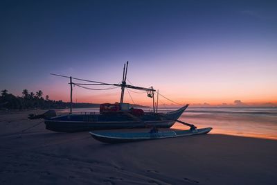 Sailboats moored on sea against sky during sunset