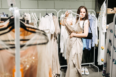 Modern latina young woman choosing 100 percent organic cotton wear in modern eco-friendly showroom.