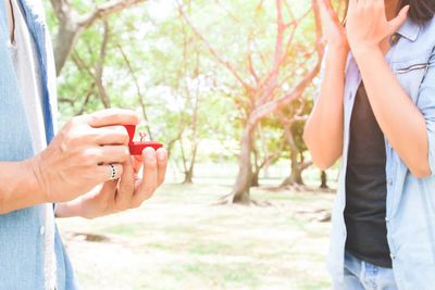 Midsection of man showing ring to woman in park