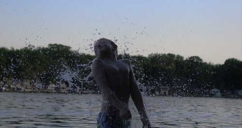 Boy playing in lake against clear sky