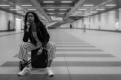 Full length of woman sitting on tiled floor