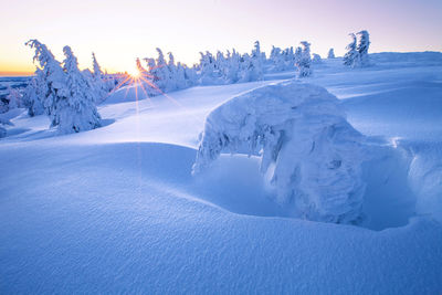 Scenic view of snow covered landscape against blue sky during sunrise