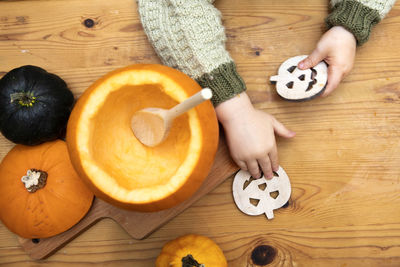 High angle view of hand holding pumpkin on table