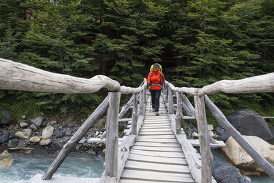 Female hiker crossing wooden bridge on the way up to torres del paine