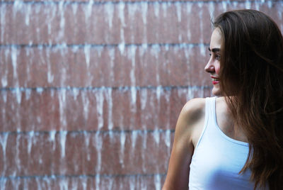 Smiling young woman looking away against wall