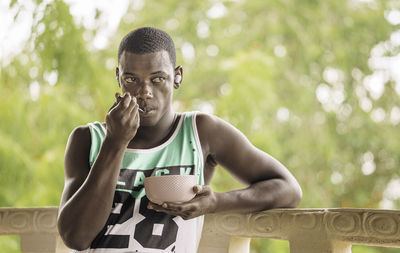 African american male with bowl of fruits listening to music and looking away while having breakfast