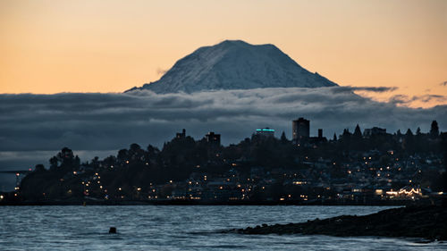 Scenic view of sea and buildings against sky at sunset