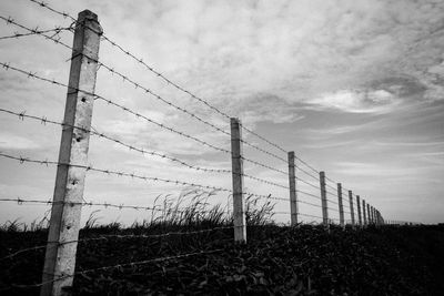 Low angle view of fence on field against sky