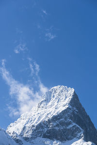 Low angle view of snowcapped mountain against blue sky