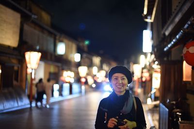 Portrait of smiling man standing in illuminated city at night