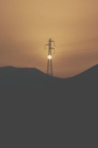 Silhouette electricity pylon against sky during sunset