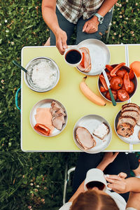 Family having breakfast outdoors on camping during summer vacation. table setting set on grass