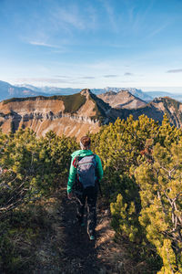 Rear view of man cycling on mountain against sky