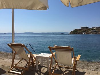 Chairs and tables on beach against clear sky