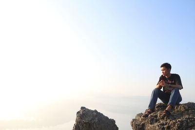 Full length of man sitting on rock