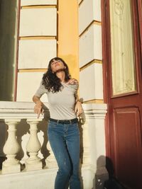 Portrait of young woman standing against building