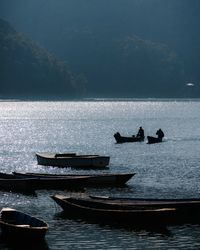 Silhouette boats moored in sea against sky