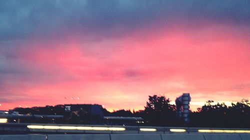 Cars on road against cloudy sky at sunset