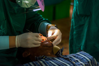 Midsection of male dentist operating patient in hospital