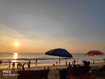 People on beach against sky during sunset