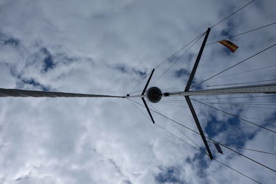 Low angle view of bird on cable against cloudy sky