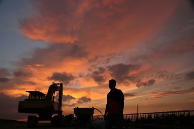 Silhouette man standing against orange sky during sunset