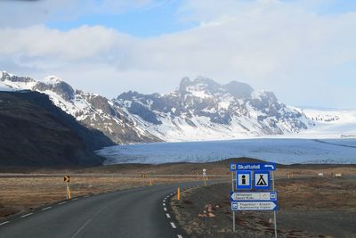 Road by snowcapped mountains against sky