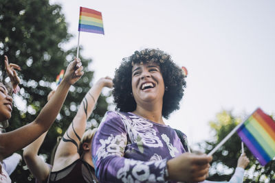 Happy transgender woman with rainbow flag enjoying in gay pride parade