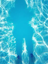 Low section of person with shadow standing on swimming pool