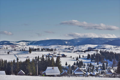 Scenic view of townscape by mountains against sky