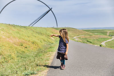 Full length of girl standing on road against sky