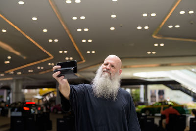 Man holding camera while standing on illuminated ceiling