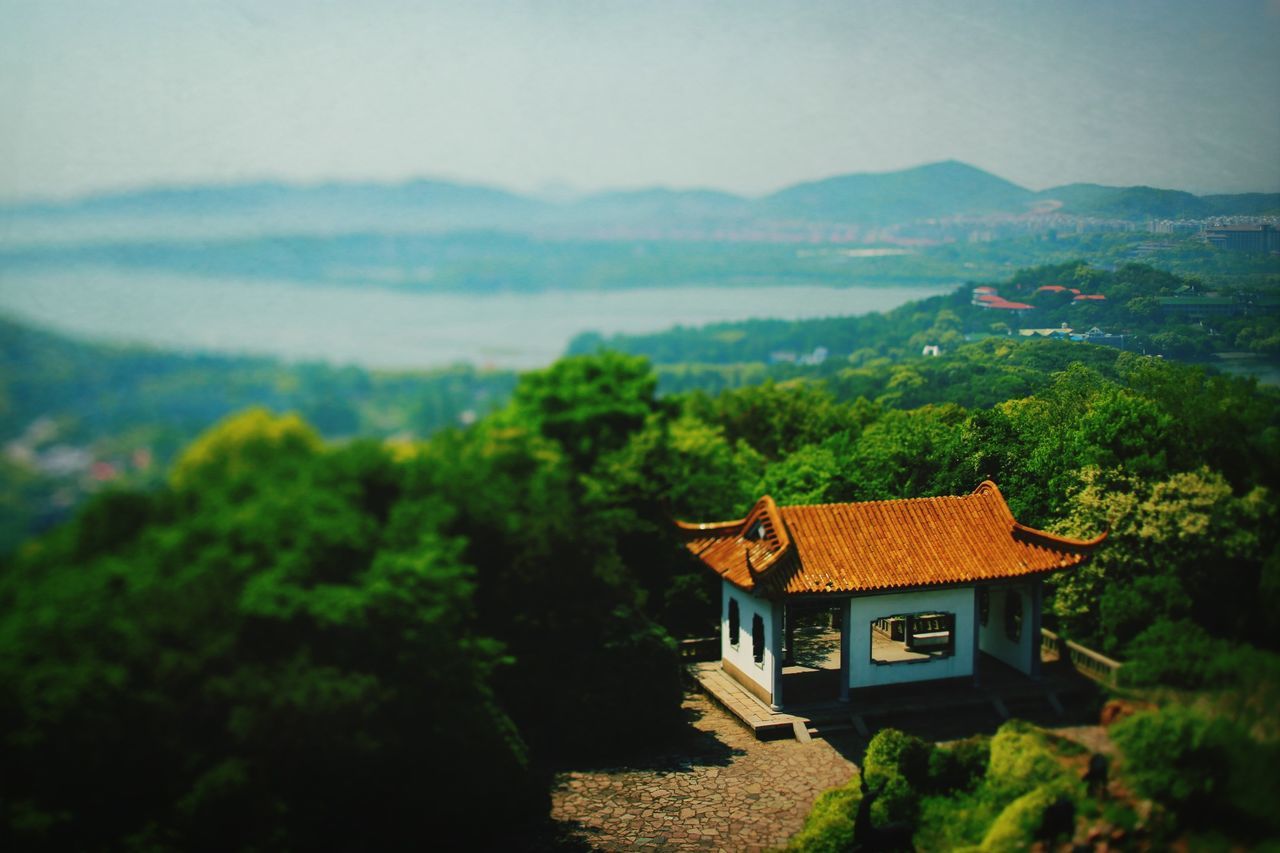 building exterior, architecture, built structure, mountain, tree, house, high angle view, residential structure, roof, hill, residential building, scenics, nature, town, lush foliage, clear sky, landscape, tranquil scene, sky, beauty in nature