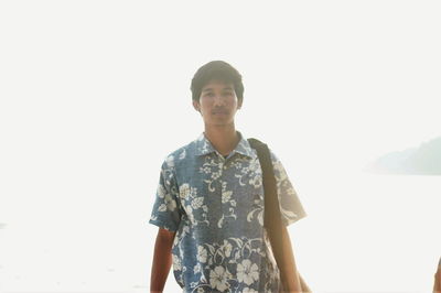 Portrait of young man standing against clear sky