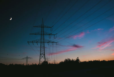 Low angle view of silhouette electricity pylon against sky during sunset