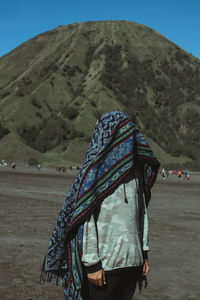 Rear view of people walking on land against mountain