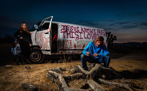 People on land by car against sky