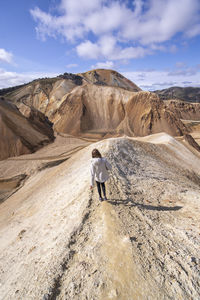 Rear view of man standing on mountain against sky