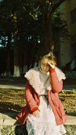 Young woman sitting on retaining wall during sunny day