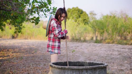Woman holding umbrella while standing by plants
