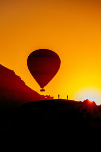 Silhouette of hot air balloon against orange sky