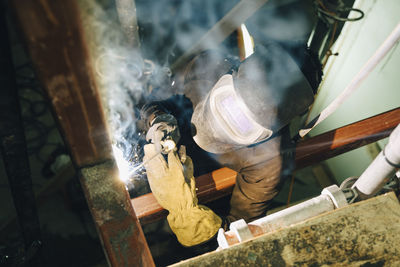 Young worker using welding torch while working at site