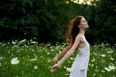 Young woman standing against plants