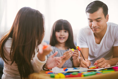 Portrait of smiling girl being taught by parents in living room